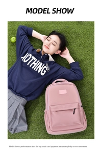 Detailed view of pink school backpack on grass featuring large main pocket and front zipper