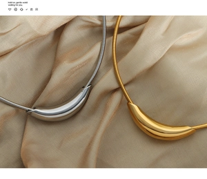 Detail of gold and silver curved crescent pendants on snake chains over silk fabric