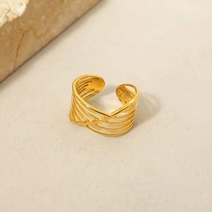 Macro detail of multilayer hollow gold ring on minimalist beige stone background