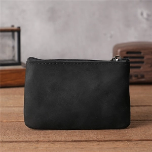 Gros plan d'un porte-monnaie vintage en cuir noir avec fermeture éclair sur bureau en bois