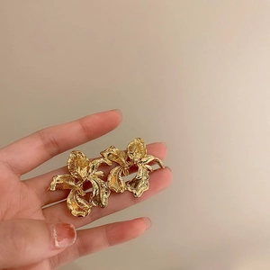 Macro detail of irregular gold floral earrings with textured metallic petals and vintage design
