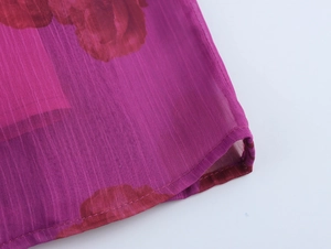 Gros plan du tissu mousseline avec texture verticale et imprimé floral sur robe fuchsia