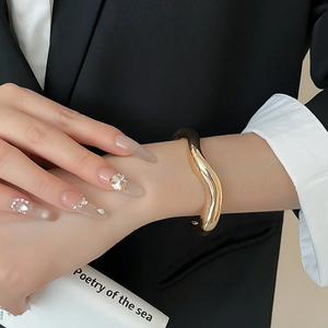 Close-up of wavy gold open cuff bracelet styled with professional business attire