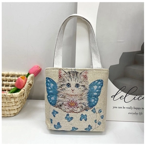 Detailed embroidery of cat with butterfly wings on beige canvas tote with silver handles