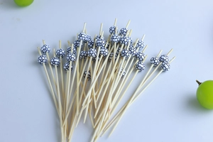 Bamboo fruit picks with black and white football beads on plain white background