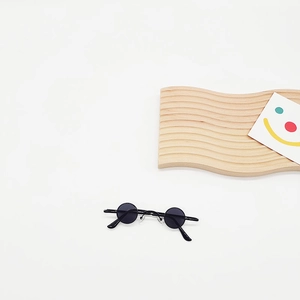 Detailed view of mini black round sunglasses with thin frame and vintage circular lenses