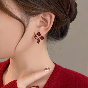 Vintage enamel flower earrings in deep red with gold metal frame worn by a model