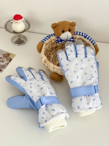Detailed close-up of winter ski gloves with blue floral patterns and ribbed windproof cuffs