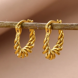 Macro detail of twisted rope hoop earrings in 18k gold plating on a natural branch