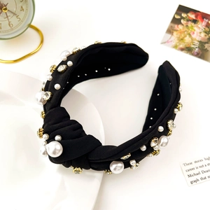 Detail of luxury black knotted headband with white pearls and sparkling rhinestones