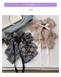 Floral chiffon bow hair claws in pink and navy blue with long ribbons on a white desk