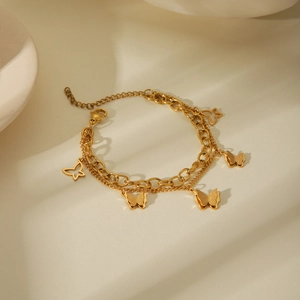 Detail of 18k gold layered stainless steel bracelet with textured butterfly charms