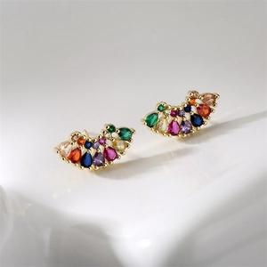 Vue macro de boucles d'oreilles dorées en éventail avec zircons colorés en forme de goutte