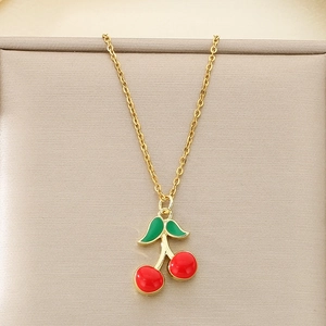Close-up of red cherry pendant with green leaves on gold chain necklace
