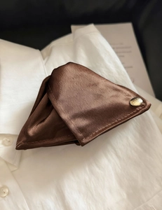 Détail du tissu en satin marron et du bouton en métal doré sur cette pince à cheveux