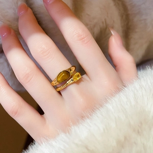 Detail of gold plated ring set with oval tiger eye stone and yellow teardrop crystal