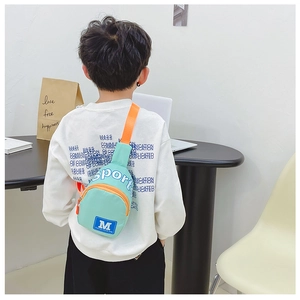 Vue arrière d'un enfant portant un sac bandoulière en nylon vert menthe et orange Sport
