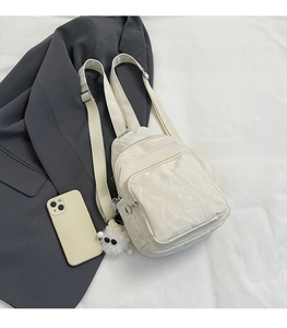 Confronto dimensioni di un piccolo zaino beige multifunzionale accanto a uno smartphone