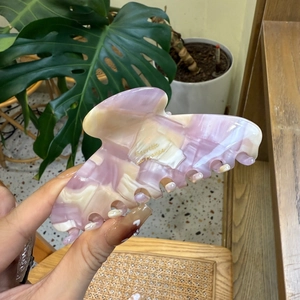 Detail of acetate hair claw clip with purple marble pattern and gold lettering