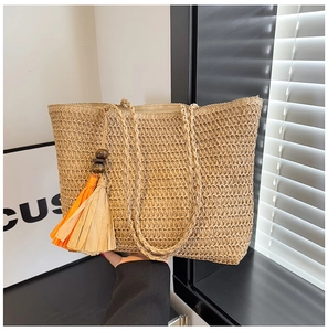 Detail of straw tote bag with rainbow stripes and decorative orange tassel accents