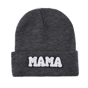 Detail of dark grey knit beanie featuring white MAMA towel embroidery on the cuff