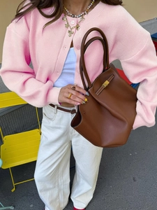 Close-up of brown leather tote bag with elegant metallic buckle and durable handles