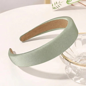 Detailed close-up of a light green padded satin headband with non-slip inner lining