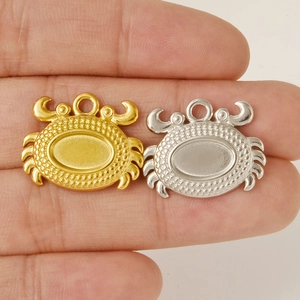 Detailed view of 18K gold and silver crab pendants held on fingers for DIY jewelry making