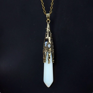 Close-up of hexagonal opal pendant with vintage bronze filigree cap on a black background