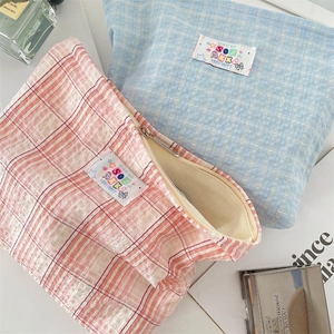Dettaglio di pochette trucco a quadretti in cotone blu e rosa con etichetta logo