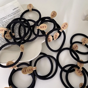 Close-up of seamless high-elasticity black hair ties displayed on a white ceramic plate