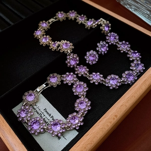 Macro shot of purple rhinestone flower necklace set on black velvet display tray