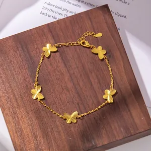 Detail view of golden butterfly charm bracelet with radial brushed finish on dark wood
