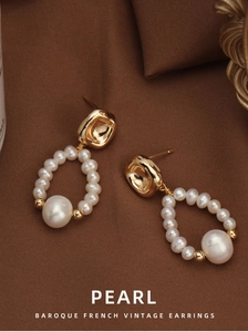 Macro shot of Baroque freshwater pearl earrings on vintage textured fabric background
