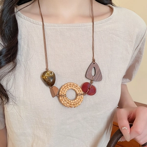Detail of bohemian necklace with woven rattan ring and amber resin geometric pendants