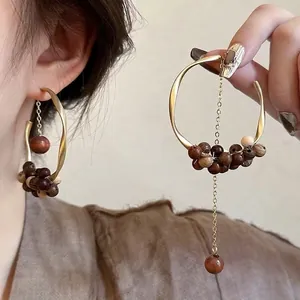 Vintage round rattan wooden bead drop earrings with gold metal accents on model