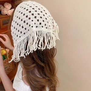 Detail view of cream crochet triangle scarf with hollow patterns and long fringes on hair