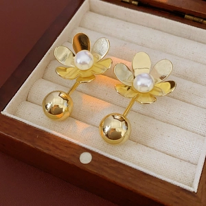 Détail de boucles d'oreilles fleur en or avec perles blanches dans un écrin en velours