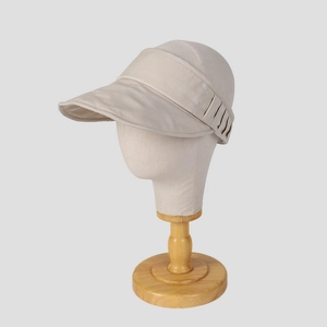 Detail view of beige fabric sun visor featuring elastic back strap and subtle texture