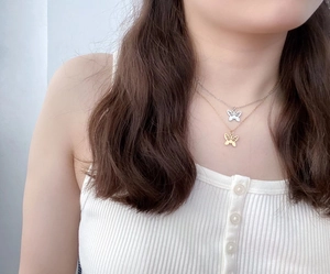 Detailed view of layered stainless steel necklace with silver and gold butterfly pendants