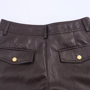 Detalle de pantalones de cuero marrón oscuro con bolsillos traseros y botones dorados
