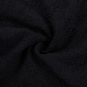 Vue macro détaillée du tissu jacquard noir avec texture florale gaufrée et crêpe