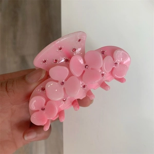 Detail of pink acetate hair claw clip with delicate flower design and sparkling rhinestones