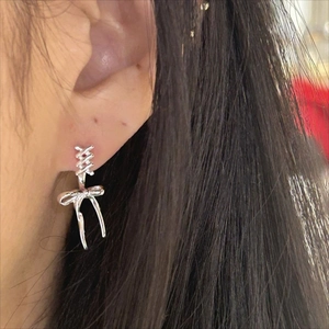 Close-up of a silver bow drop earring worn by a model showing its elegant tassel design