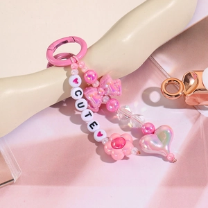 Gros plan sur un porte-clés rose perlé avec un nœud papillon et un pendentif en cœur