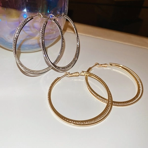 Detail of silver and gold interlaced hoop earrings with sparkling diamond pavé accents