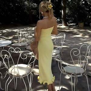 Vista posteriore dell'abito giallo a fascia con balze in un giardino all'aperto