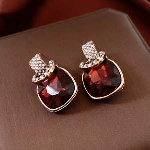 Macro shot of vintage square stud earrings with dark red crystal and sparkling rhinestones