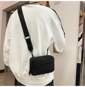 Detail of black rectangular crossbody bag showing the adjustable wide nylon strap and back fit