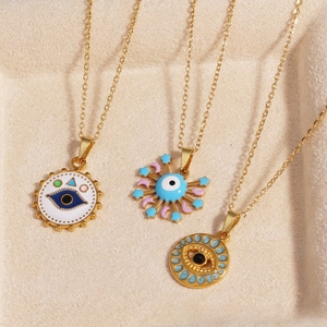 Detailed view of three gold evil eye pendants with colorful enamel on a beige tray